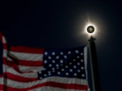 Un eclipse solar total se ve junto a una bandera estadounidense ondeando en Houlton, Maine, EE.UU. 8 de abril de 2024.