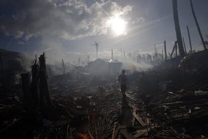Un hombre camina entre el humo y los escombros en Tolosa, una de las zonas devastada por el tifón Haiyan, que arrasó parte de Filipinas en noviembre de 2013.