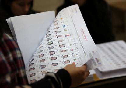 Una mujer sujeta la lista de los candidatos a las elecciones generales en Quito.