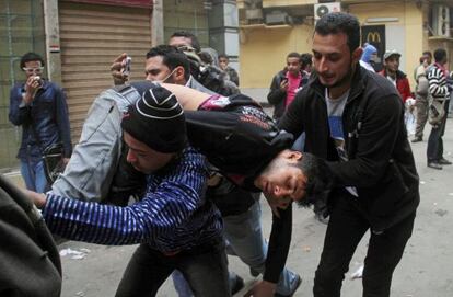 Dos manifestantes llevan a un herido esta ma&ntilde;ana en El Cairo.