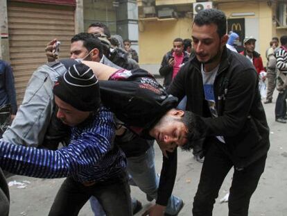Dos manifestantes llevan a un herido esta mañana en El Cairo.