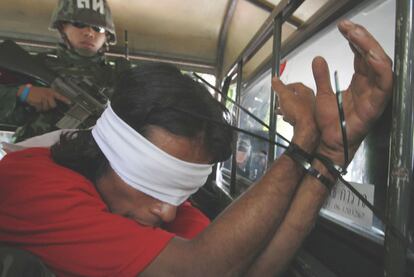 Un soldado tailands custodia a un <i>camisa roja</i> detenido en un templo budista en Bangkok.