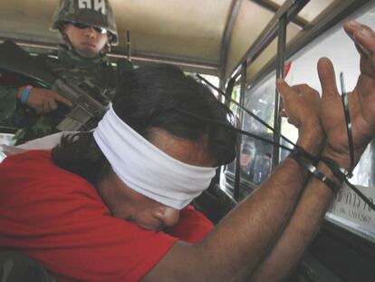 Un soldado tailandés custodia a un <i>camisa roja</i> detenido en un templo budista en Bangkok.