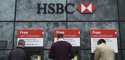 Tres clientes sacan dinero en los cajeros del banco británico HSBC.