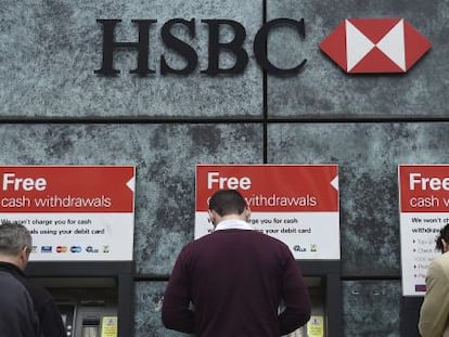 Tres clientes sacan dinero en los cajeros del banco británico HSBC.