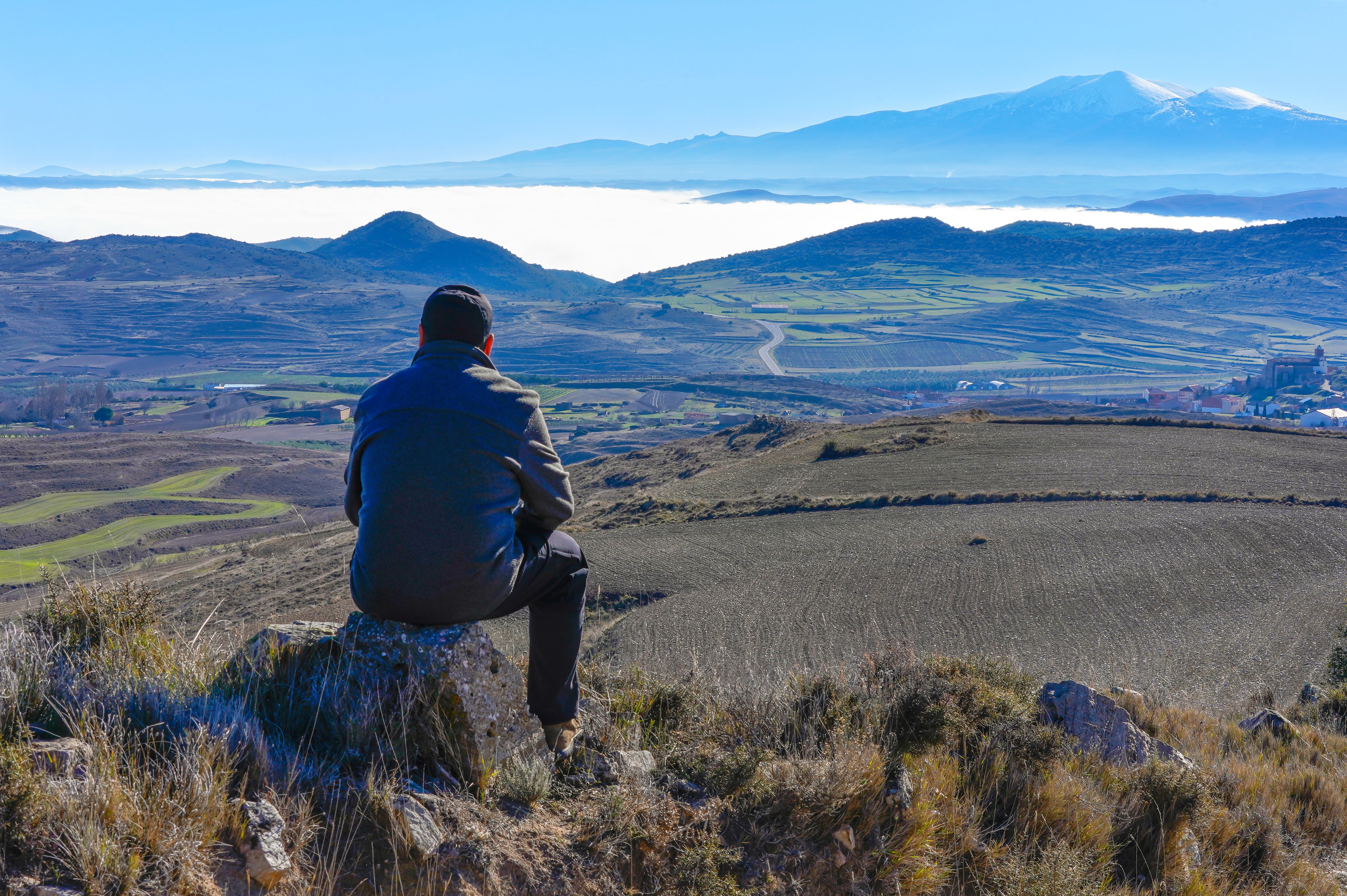 Un hombre observa el paisaje de montañas nevadas y valles con nieblas de la sierra del Moncayo. 