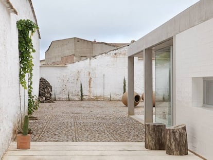 Una vez en el patio empedrado, por el que se llega al traspasar la puerta metálica que da a la calle,  dos troncos marcan el acceso lateral a la vivienda.