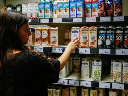 Una mujer mira bebidas verdes en un supermercado de Madrid.