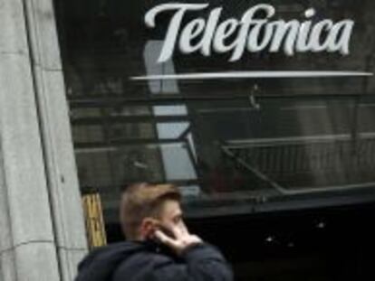 Un hombre habla por su m&oacute;vil junto a la sede de Telef&oacute;nica en Gran V&iacute;a.