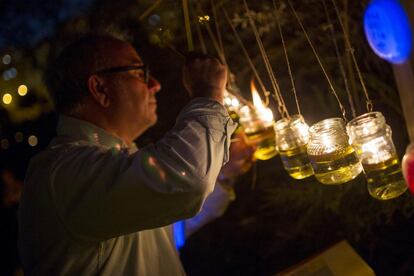 Un participante del proyecto Alumbra Sevilla en el Parque de Miraflores enciende las lámparas de aceite.