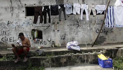 Un panameño lee el periódico frente a la ropa tendida.