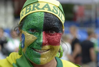 Um torcedor da seleção alemã, com a cara pintada com as cores de Brasil e Alemanha, espera o início do jogo.