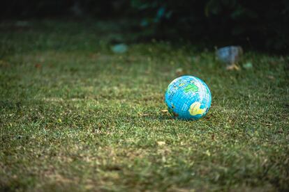 Una pelota con la imagen de un mapamundi reposa sobre el cesped.