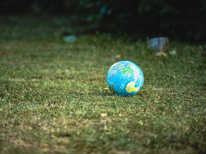 Una pelota con la imagen de un mapamundi reposa sobre el cesped.