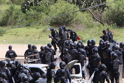 Policías antidisturbios retiran a un oficial herido durante el entrentamiento con profesores que bloqueaban una carretera federal en Oaxaca.