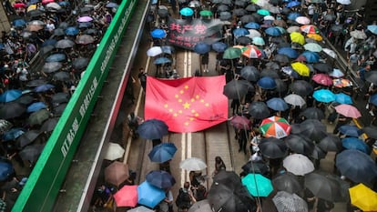 Manifestantes marchan con una pancarta que usa las estrellas de la bandera nacional china para rerpresentar una esvástica nazi. 