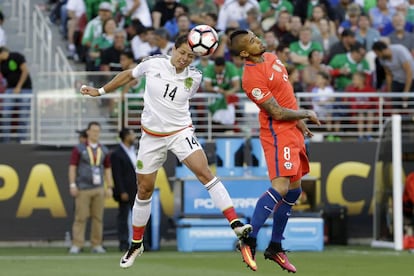 Chicharito y Vidal saltan a por un balón.