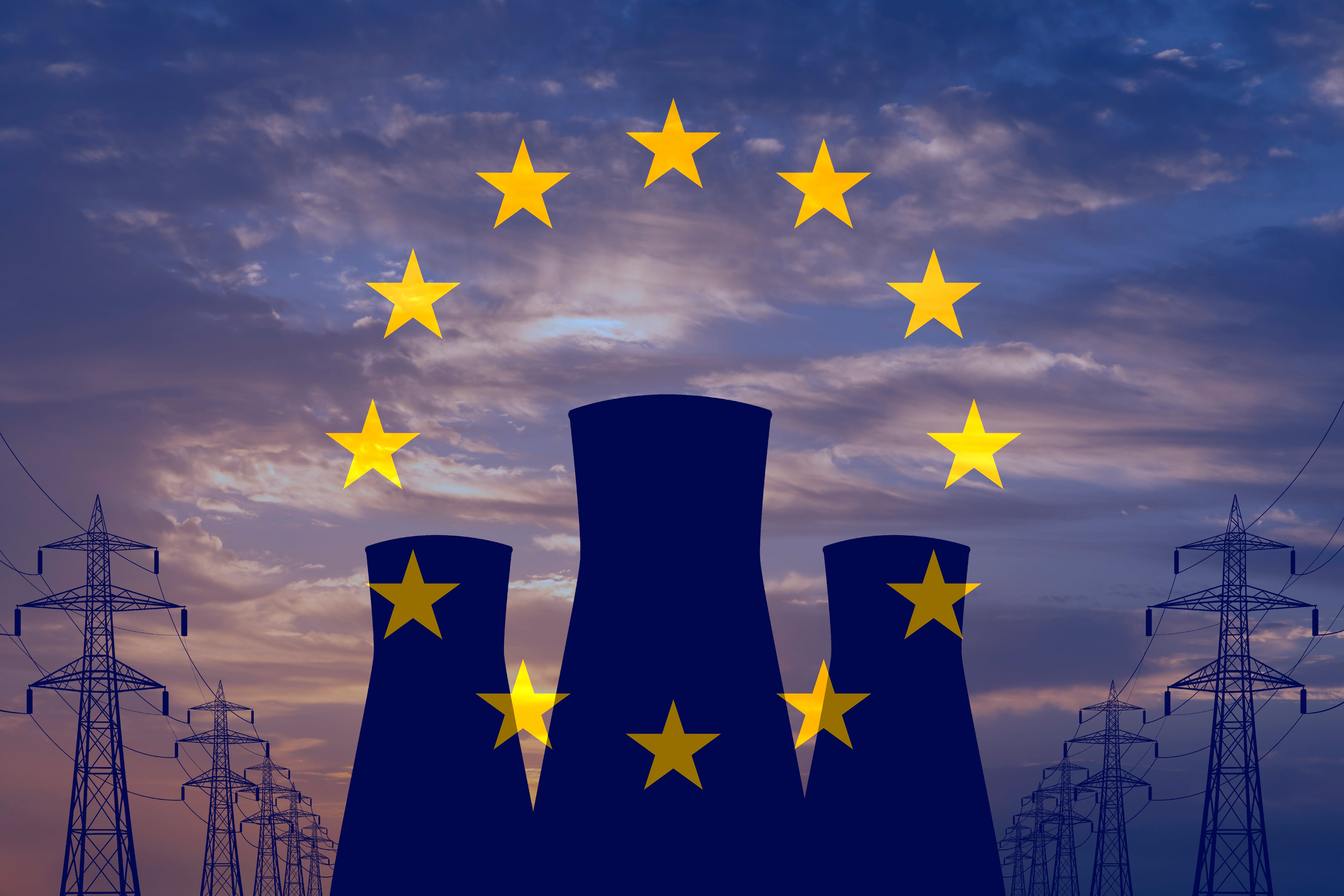 Las chimeneas de una central nuclear con la bandera de la UE de fondo