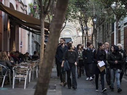 Un grupo de personas pasea por delante de las terrazas de la calle Torrijos, en el barrio de la Vila de Gr&agrave;cia