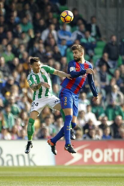 Piqué (derecha), del Barcelona, salta para golpear el balón de cabeza junto con Rubén Castro, del Betis.