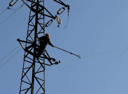 Un operario trabaja sobre una torre de media tensión, retirando el cable caído sobre la catenaria.