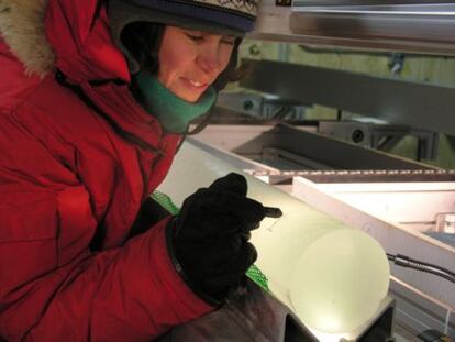 Una investigadora observa un testigo de hielo obtenido a 500 metros de profundidad en la Antártida.