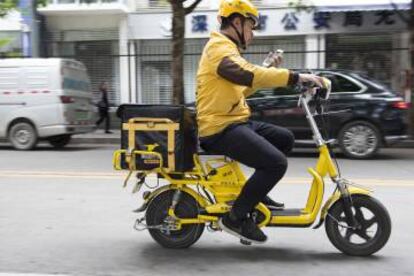 Un mensajero de Waimai comprueba la dirección a la que lleva comida a domicilio a bordo de una bicicleta eléctrica.