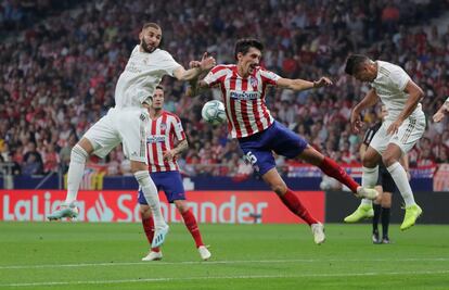 Stefan Savic (en el centro), del Atlético de Madrid, defiende una pelota frente a Casemiro (a la derecha) y Karim Benzema, del Real Madrid.