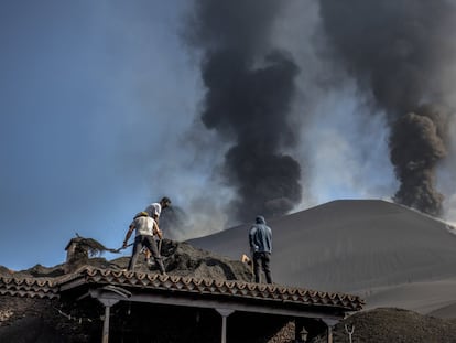 Dos vecinos retiran a pala la ceniza que cubre casi totalmente una casa en Las Manchas, en La Palma, el pasado día 16.