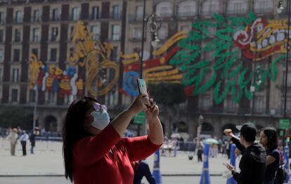 Una mujer usa su teléfono móvil en la explanada del zócalo capitalino