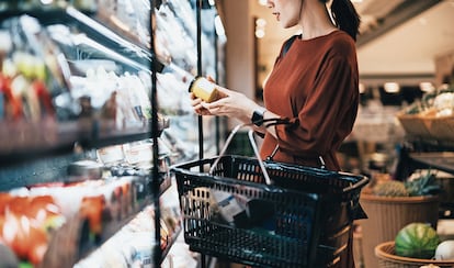 Una mujer consulta la información de la etiqueta de un producto en un supermercado.