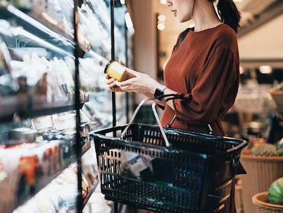 Una mujer consulta la información de la etiqueta de un producto en un supermercado.
