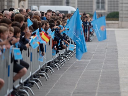 Un grupo numeroso de personas aguarda al paso de la comitiva junto al Palacio Real, este martes en Madrid.