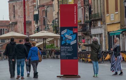 Turistas observan ayer lunes un cartel que anuncia la 57&ordf; Bienal de Venecia.