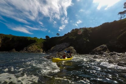 Dos clientes salen en una canoa doble de una de las cuevas a las que se accede en la parte asturiana de la ría.