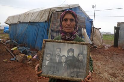 Una desplazada siria muestra una foto familiar en una aldea de Idlib.