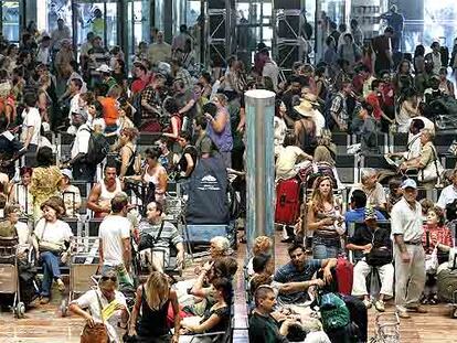 Cientos de pasajeros esperan sus vuelos ayer en el aeropuerto de El Prat de Barcelona.
