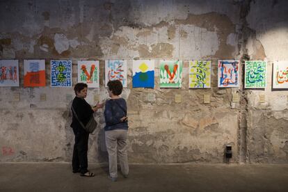 Dos mujeres dialogan frente a las serigrafías de dos diseñadores gráficos, en la muestra ‘Across Borders’ en Poblenou, Barcelona.  