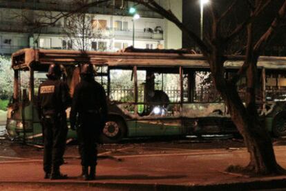 Policías delante de un autobús público quemado hace un mes por un grupo de encapuchados en Tremblay-en-France.