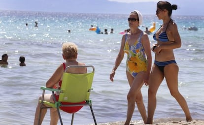 Tres turistas, en la playa de Alcudia (Mallorca).