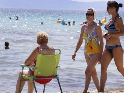 Tres turistas, en la playa de Alcudia (Mallorca).