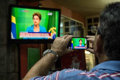 Un hombre graba en Brasil un discurso televisado de Roussef.