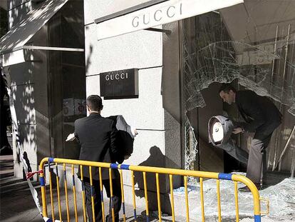 Dos dependientes retiran los maniquíes tras la luna reventada, esta mañana en la tienda de Gucci.