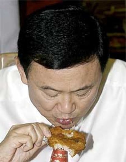 El primer ministro tailanés, Thaksin Shinawatra, come pollo rebozado para tranquilizar a la población ante el virus.