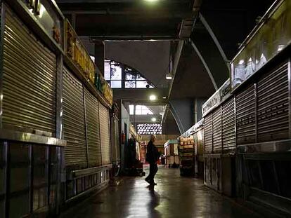 Un hombre camina entre los puestos cerrados del mercado de La Cebada, en pleno horario comercial.