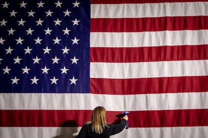 Una asistente plancha la bandera antes de iniciar la carrera presidencial en Des Moines, Iowa