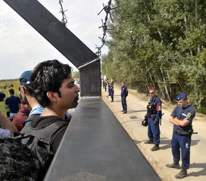 Refugiados miran a través de la valla fronteriza en lo localidad serbia de Horgos, en la frontera entre Serbia y Hungría.