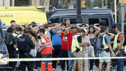 Un grupo de gente con los brazos en alto ante el despliegue policial en las Ramblas de Barcelona. 