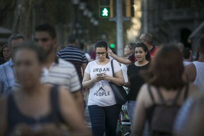 Una vianant mira el mòbil mentre creua un pas de zebra.