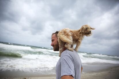 Un ciudadano, junto a su perro, visita una playa de Palm Beach antes de la llegada del huracán Matthews.